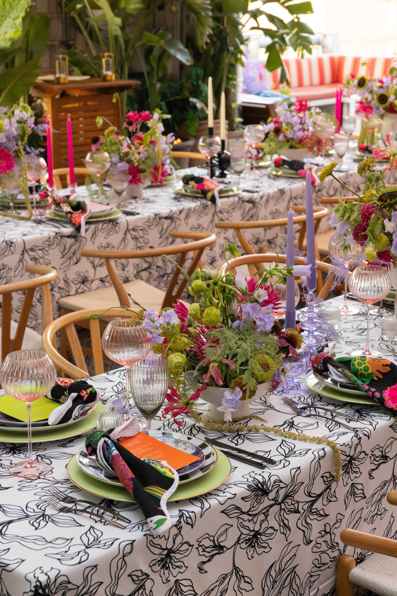 Decorative outdoor table setting with floral arrangements and colorful candles.
